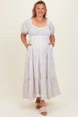 woman wearing a white puff sleeve maternity dress with tiered skirt and pockets, showing her baby bump