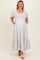 woman wearing a white puff sleeve maternity dress with tiered skirt and pockets, showing her baby bump