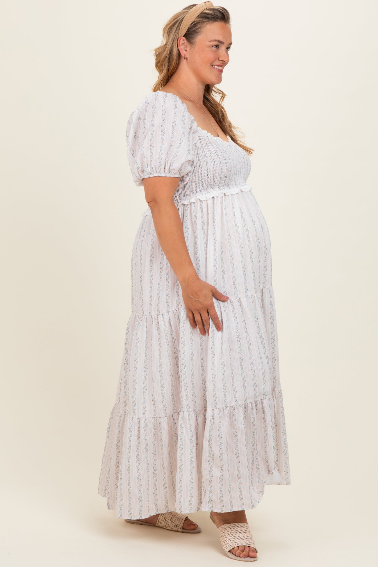 woman wearing a white striped maternity maxi dress with puff sleeves and a baby bump