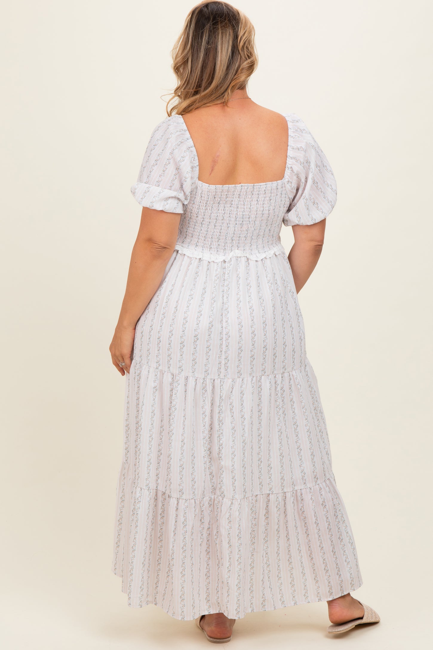 woman wearing a white floral smocked maternity maxi dress with puff sleeves, showing a relaxed fit on a baby bump