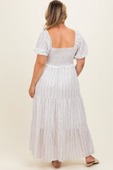 woman wearing a white floral smocked maternity maxi dress with puff sleeves, showing a relaxed fit on a baby bump