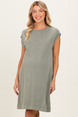 woman wearing a green cap sleeve maternity dress with side pockets and a relaxed fit showing her baby bump