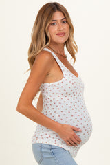 woman wearing a white maternity tank top with floral print and holding her baby bump