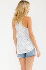 woman wearing a white tank top with blue floral print and distressed denim shorts, view from the back