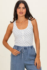 woman wearing a white sleeveless tank top with blue floral print and buttons, paired with blue drawstring pants