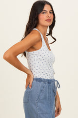 woman wearing a white floral print tank top and blue drawstring shorts