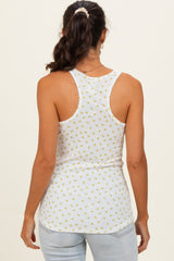woman wearing a white tank top with a small yellow floral pattern, shown from the back