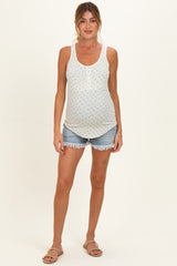 woman wearing a white maternity tank top with yellow floral print and denim shorts, showing her baby bump