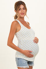 woman wearing a light gray maternity tank top with a floral pattern and showing her baby bump while wearing denim shorts