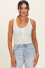 woman wearing a white floral print tank top with button details and light blue high-waisted jeans