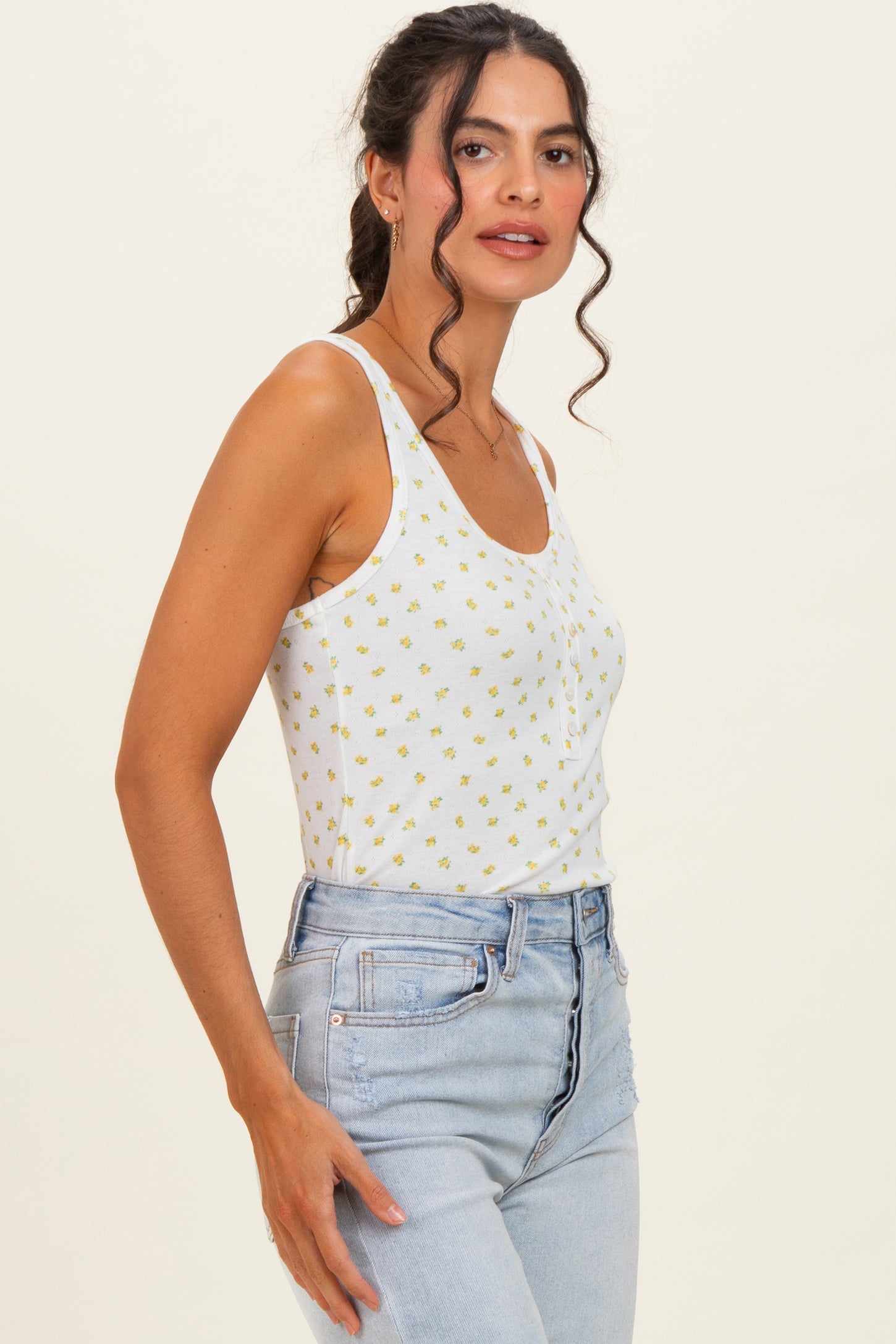 woman wearing a white floral print tank top and high-waisted light blue jeans