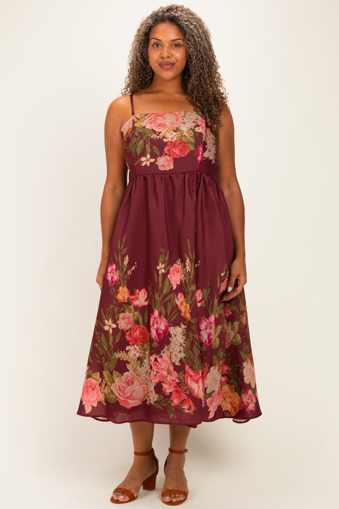 woman wearing a burgundy plus-size floral midi dress with spaghetti straps and a flowy skirt