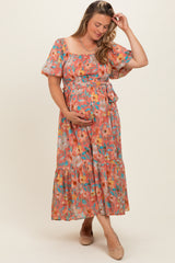 woman wearing a floral print maternity maxi dress with smocked bodice and puff sleeves, holding her baby bump