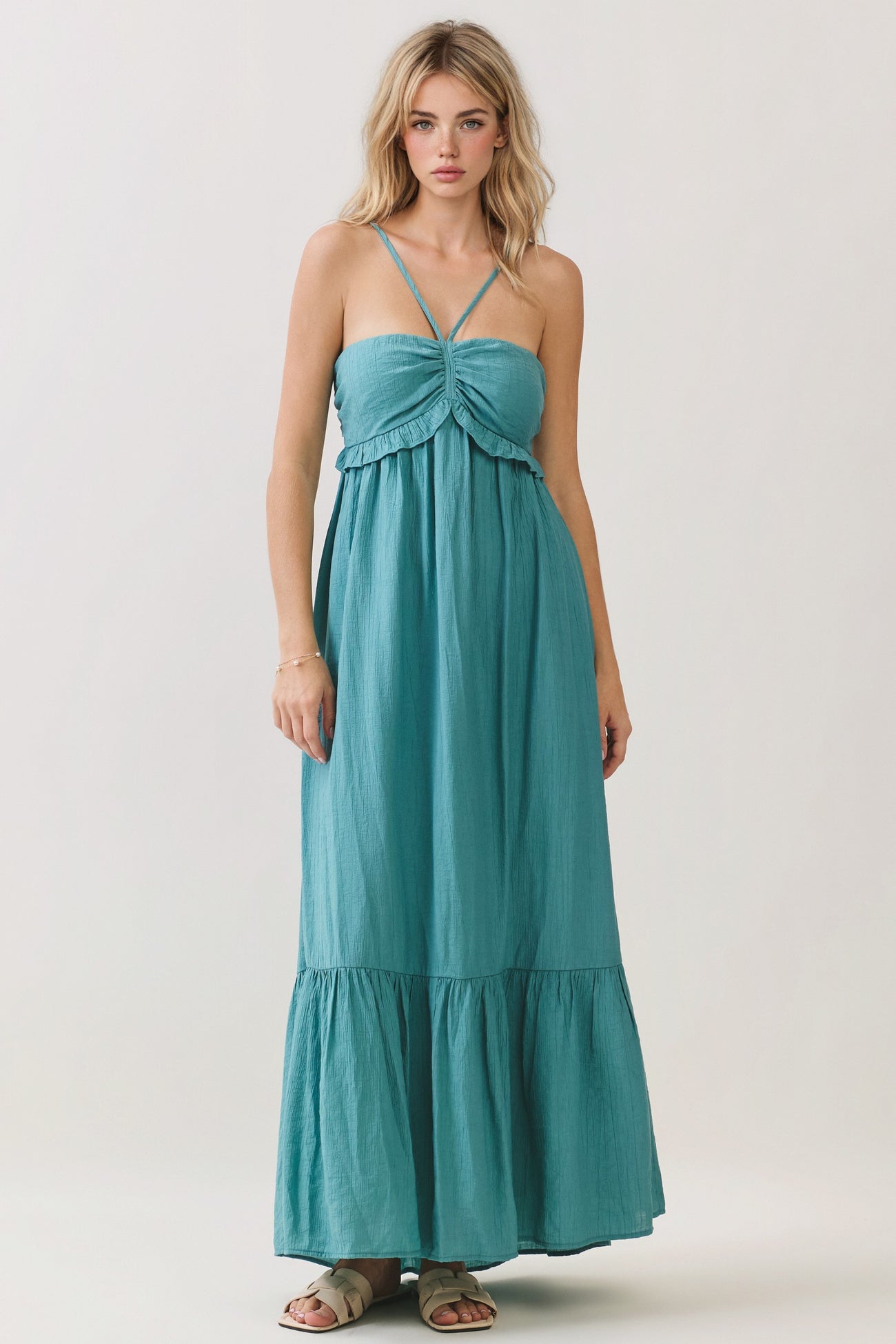 woman wearing a teal maxi dress with spaghetti straps and a ruffled bodice detail