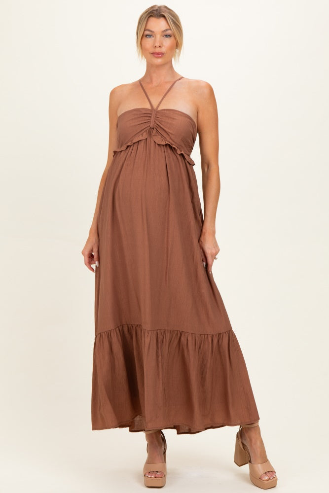 woman wearing a brown maternity maxi dress with a smocked bodice and tiered skirt, showcasing her baby bump