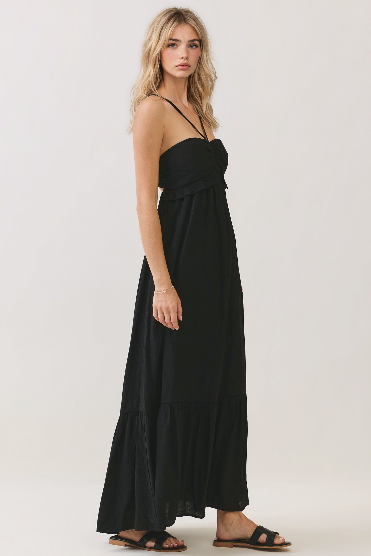 woman wearing a black strapless maxi dress with ruffle detailing and a flared hem
