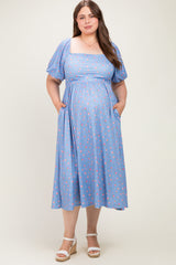 woman wearing a light blue floral maternity dress with puff sleeves and pockets, showcasing her baby bump