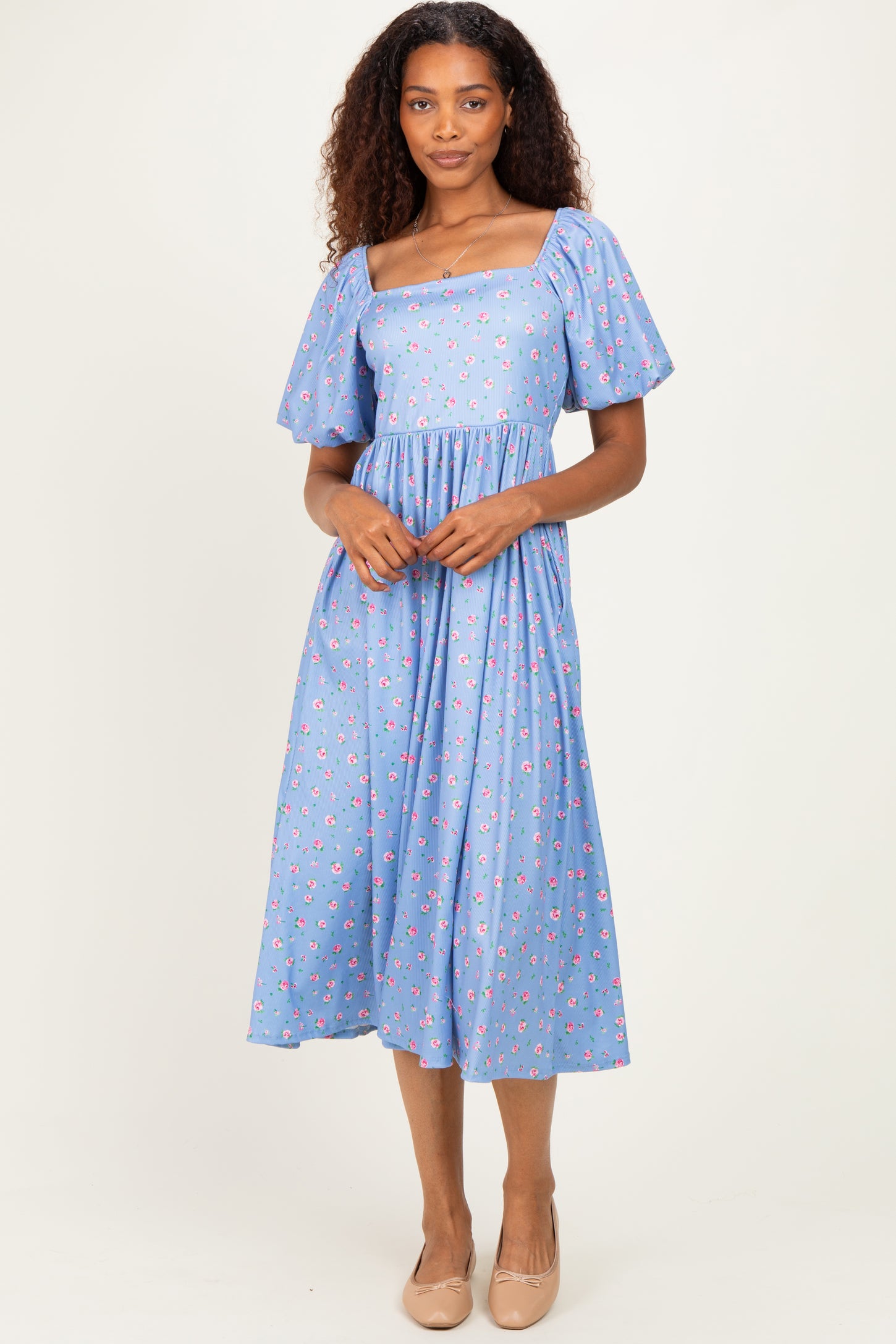 woman wearing a light blue floral midi dress with short puff sleeves and a square neckline