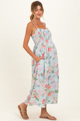 woman wearing a floral patterned maternity maxi dress with adjustable straps and pockets, showcasing her baby bump