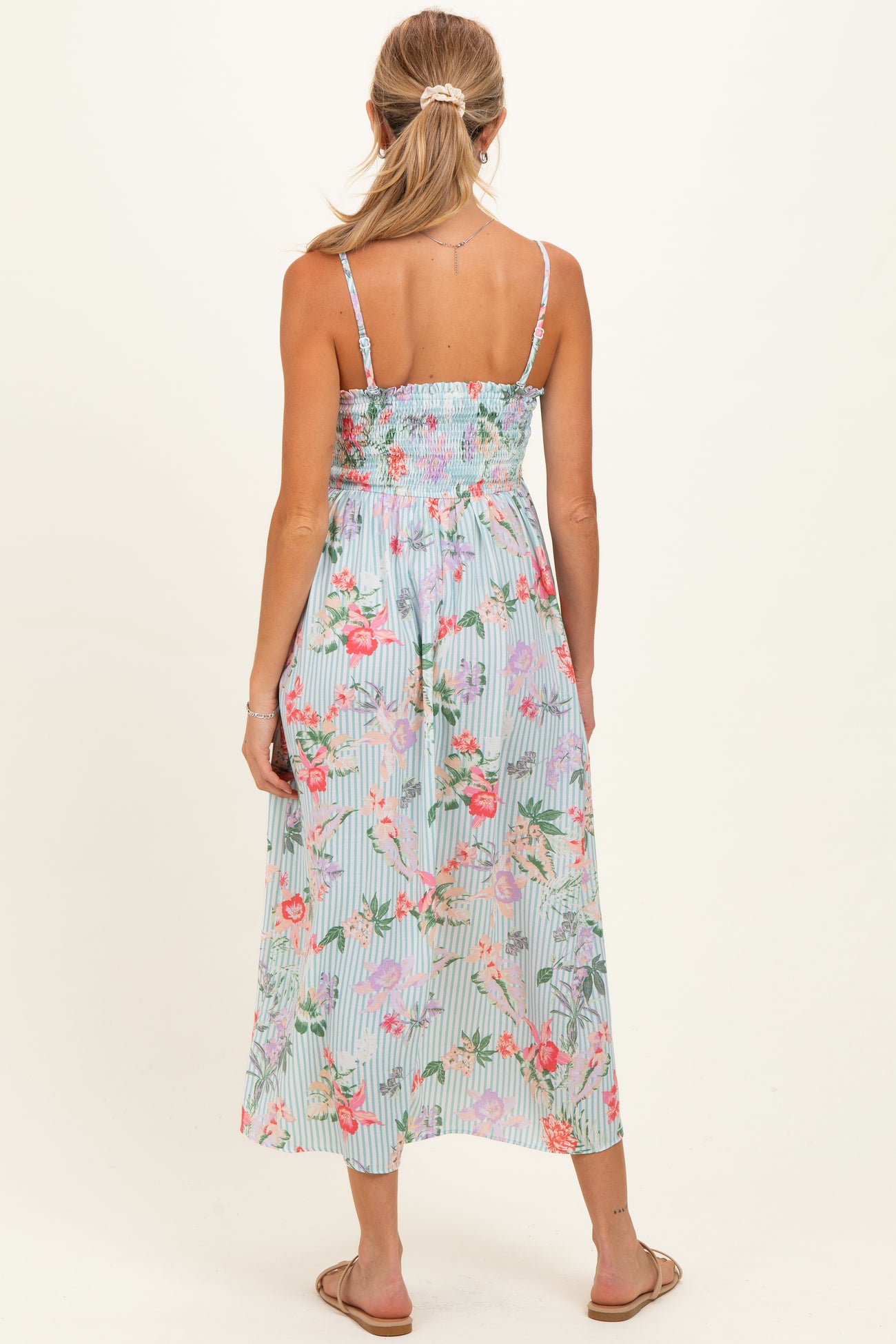 woman wearing a floral smocked back maternity dress with adjustable straps and a flowy skirt