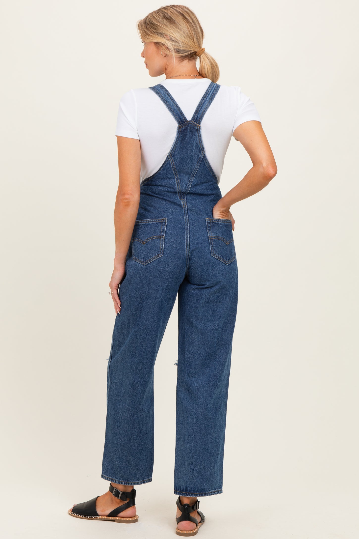 woman wearing a maternity denim overall with a white t-shirt, showing a relaxed fit and back view