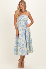 woman wearing a strapless floral print maxi dress in yellow and blue with a fitted bodice and flowing skirt