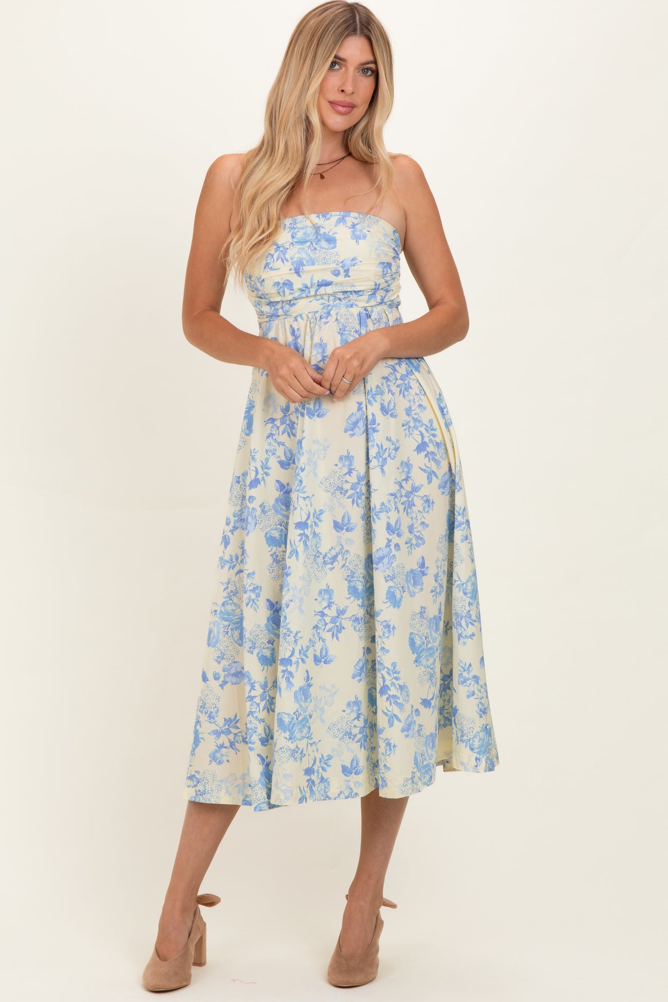 woman wearing a strapless light yellow floral midi dress with blue patterns and a fitted bodice