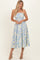 woman wearing a strapless light yellow floral midi dress with blue patterns and a fitted bodice