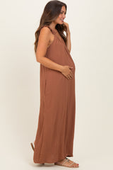 woman wearing a rust-colored maternity maxi dress with ruffle straps and holding her baby bump