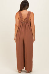 woman wearing a brown maternity jumpsuit with ruffled straps and an open back