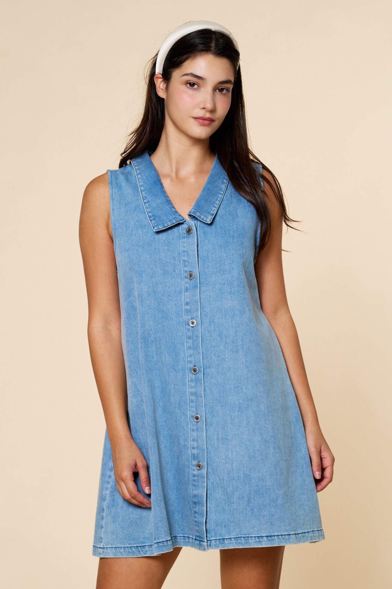 woman wearing a light blue denim sleeveless dress with a collar and buttons down the front