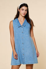 woman wearing a light blue denim sleeveless dress with a collar and buttons down the front