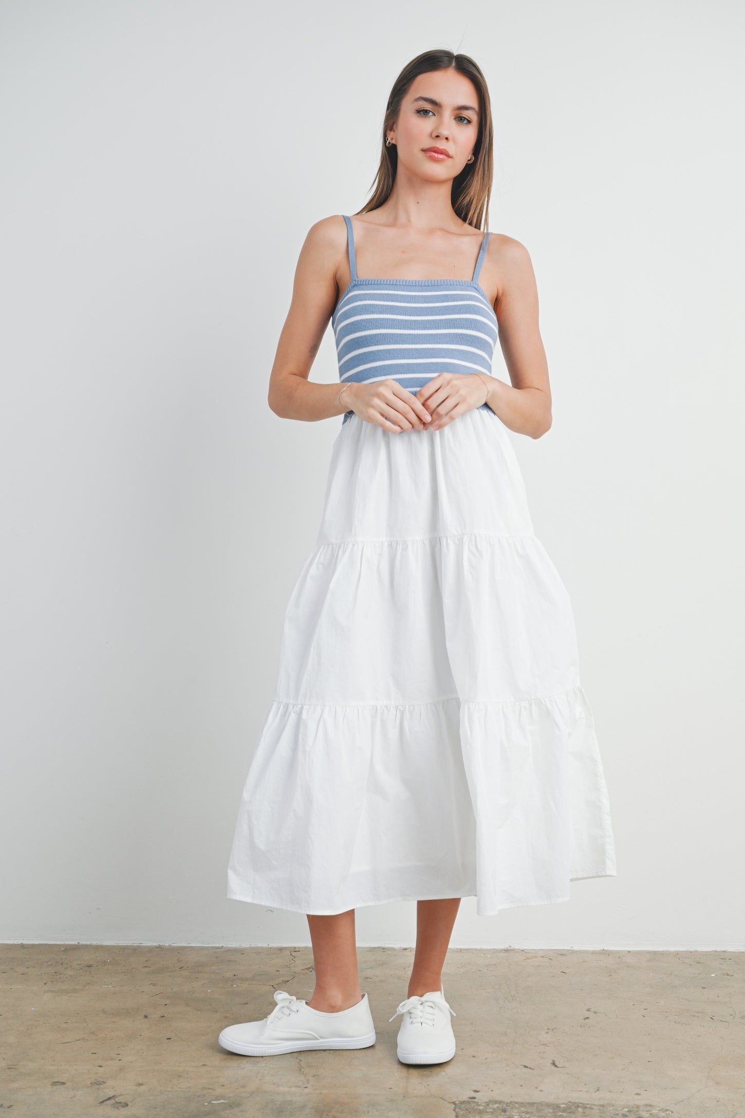 woman wearing a blue and white striped sundress with a tiered white skirt and white sneakers
