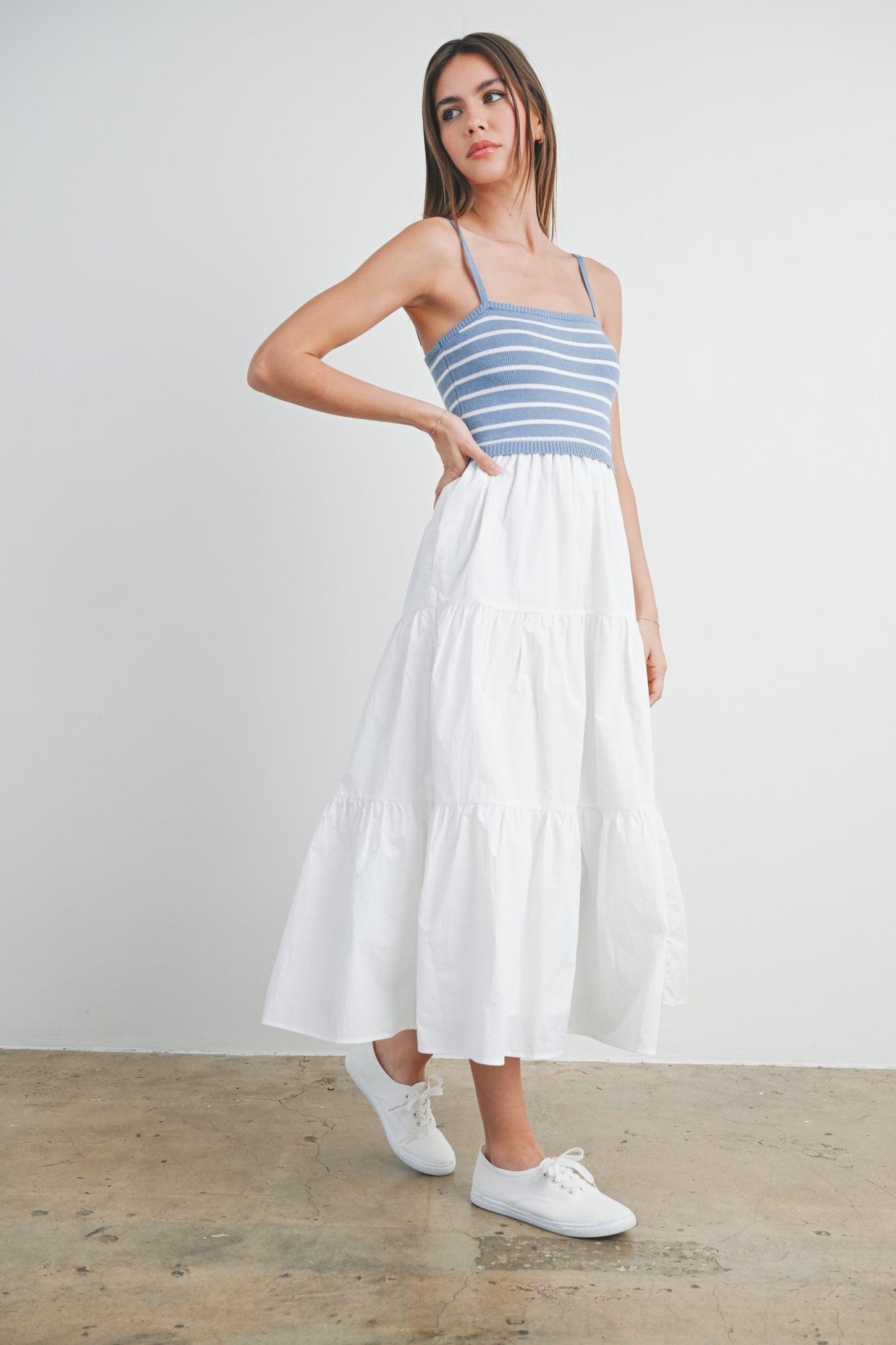 woman wearing a blue and white striped tank top with a white tiered maxi skirt and white sneakers