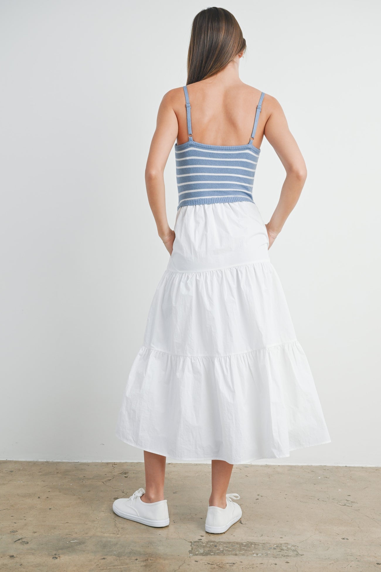woman wearing a blue and white striped tank top with a white tiered maxi skirt, seen from the back