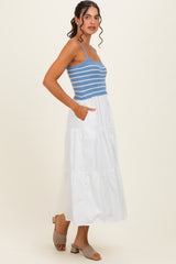 woman wearing a blue and white striped tank top and a white tiered maxi dress with pockets