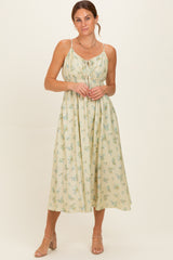 woman wearing a light yellow floral midi dress with adjustable straps and a gathered bust design