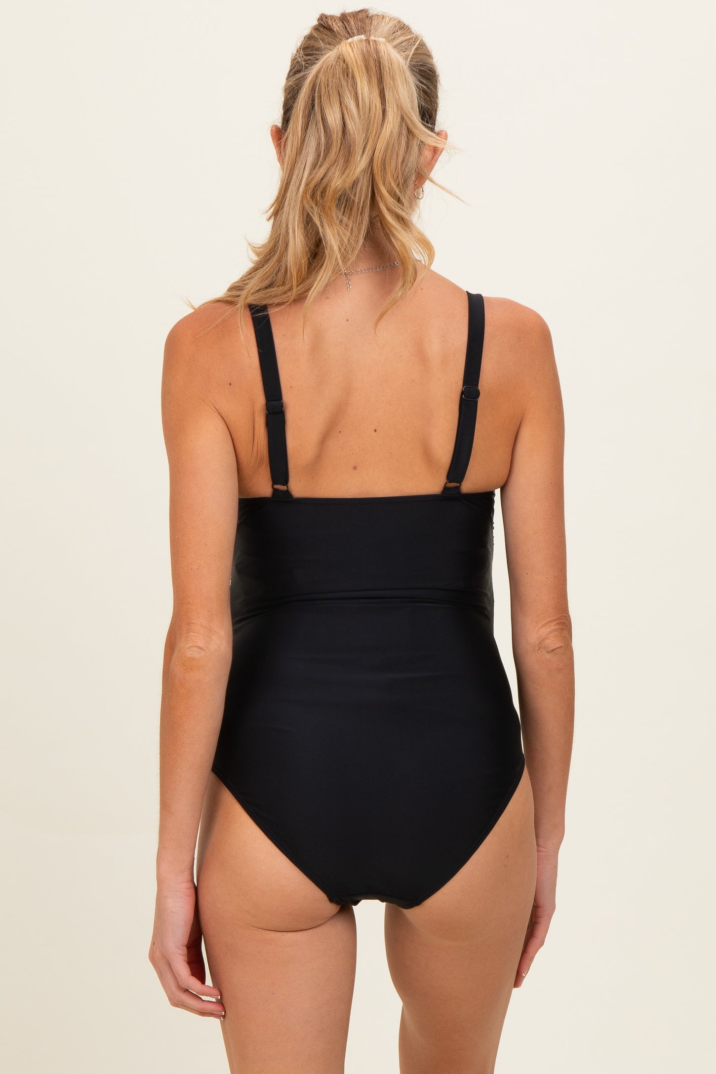 woman wearing a black maternity swimsuit with adjustable straps, showing the back view