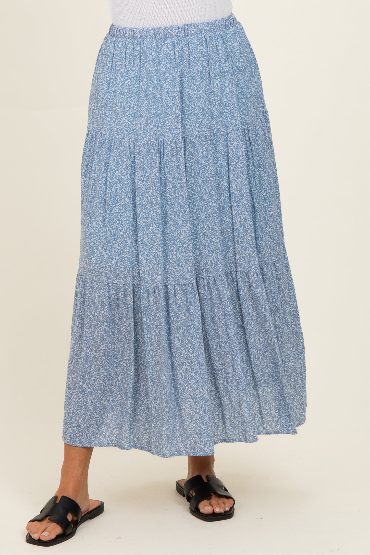 woman wearing a blue floral tiered maxi skirt with an elastic waistband and black slide sandals
