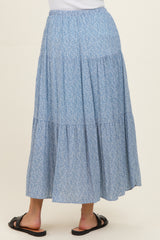 woman wearing a flowy blue floral maxi skirt with a tiered design and elastic waistband, viewed from the back