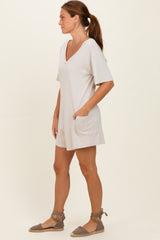woman wearing a light beige short sleeve v-neck dress with pockets and gray espadrille shoes