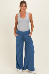 woman wearing a gray tank top and blue wide-leg maternity pants with a stretchy waistband and pockets