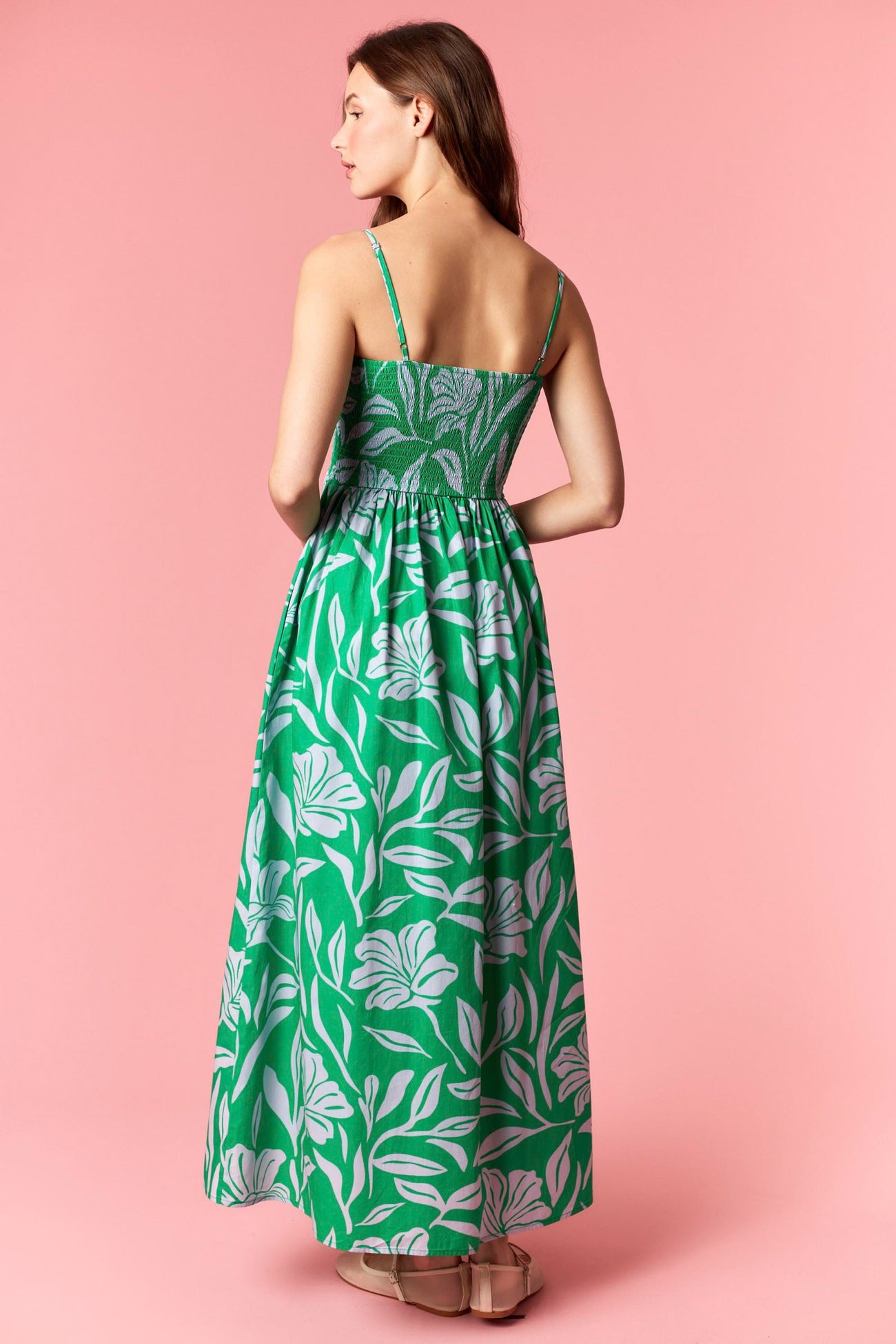 woman wearing a green floral maxi dress with a fitted bodice and flowy skirt, viewed from the back