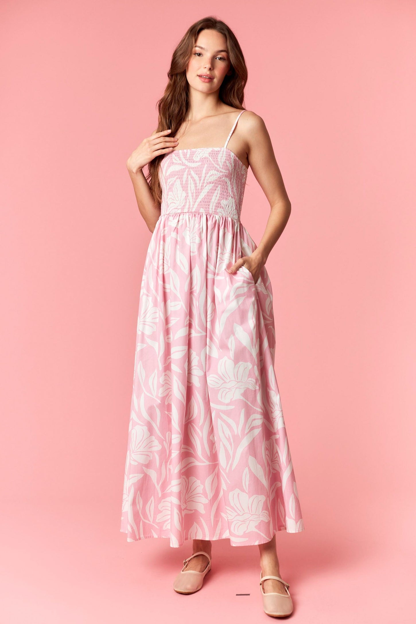 woman wearing a pink floral maxi dress with adjustable straps and pockets