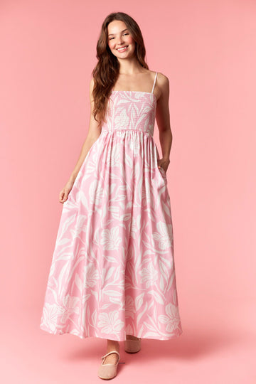 woman wearing a pink floral maxi dress with adjustable spaghetti straps and pockets