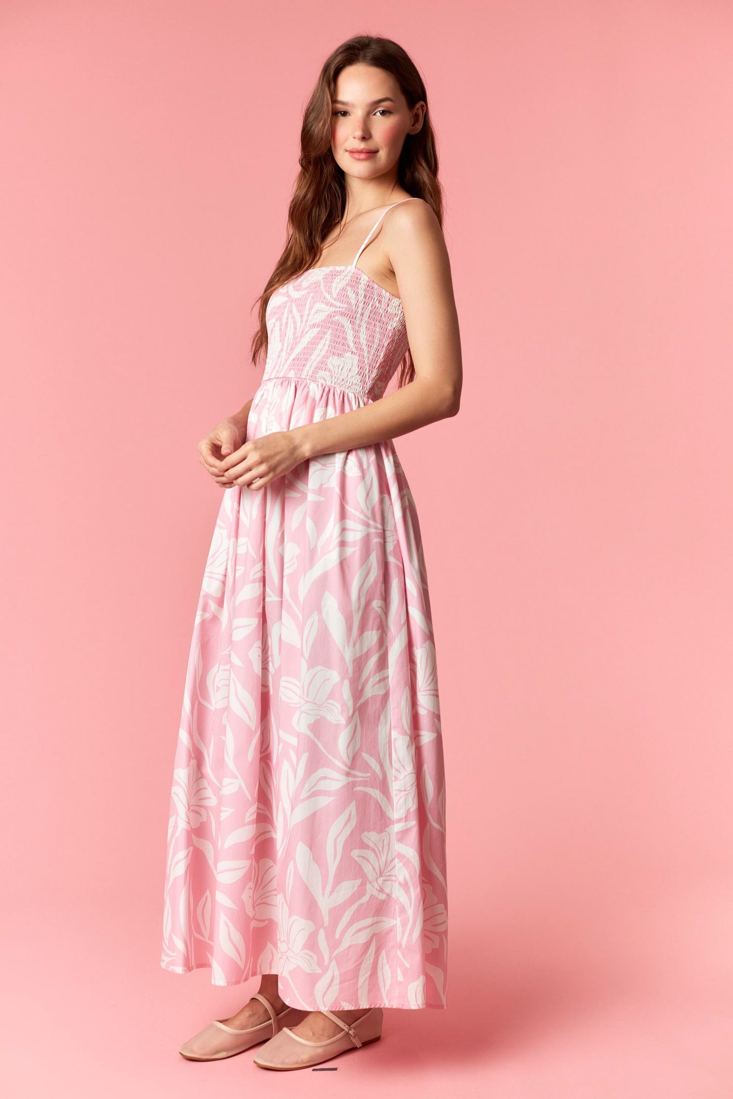 woman wearing a pink floral maxi dress with spaghetti straps and a fitted bodice