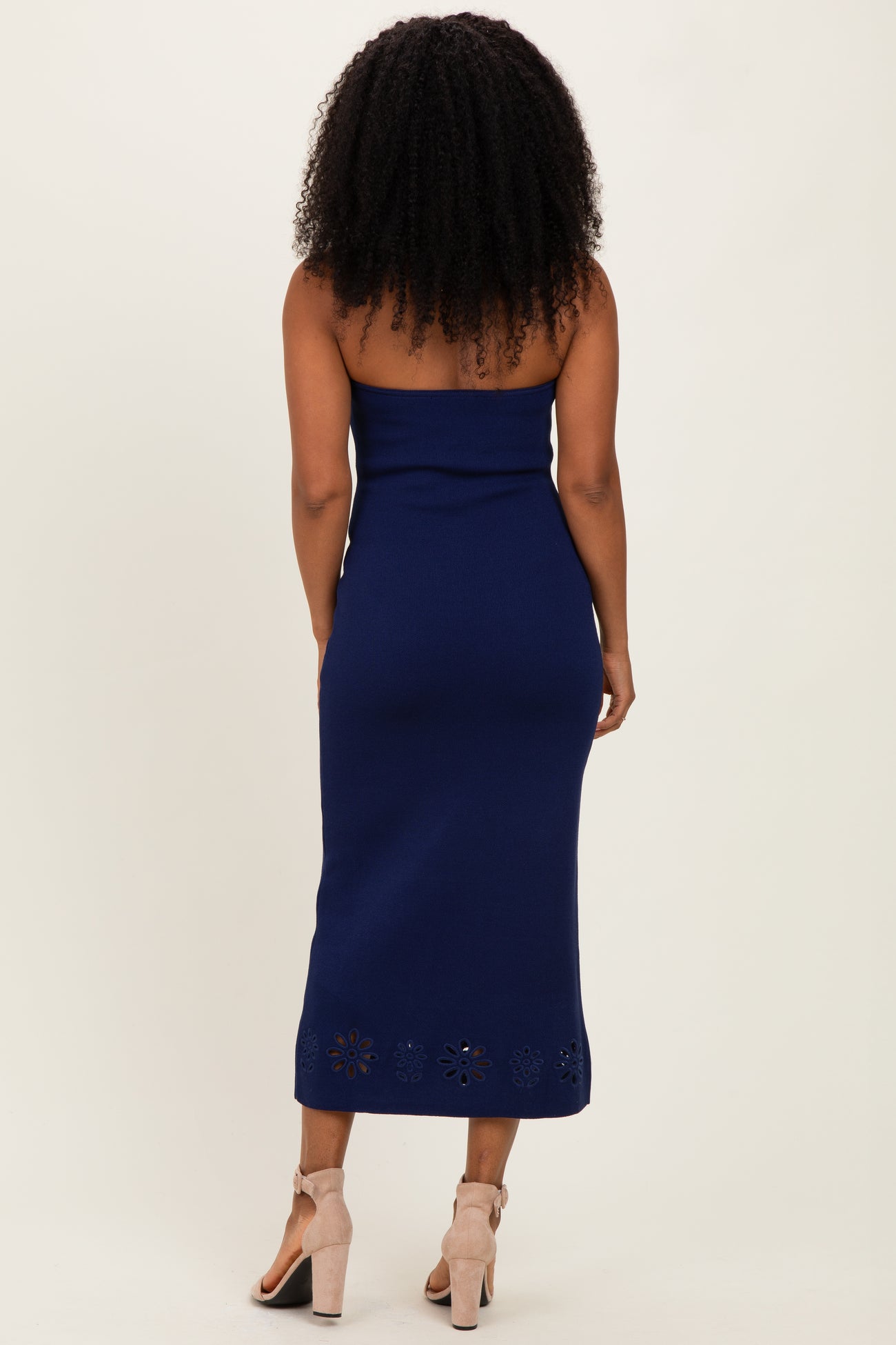 woman wearing a navy blue strapless midi dress with a floral cut-out hem and a fitted silhouette