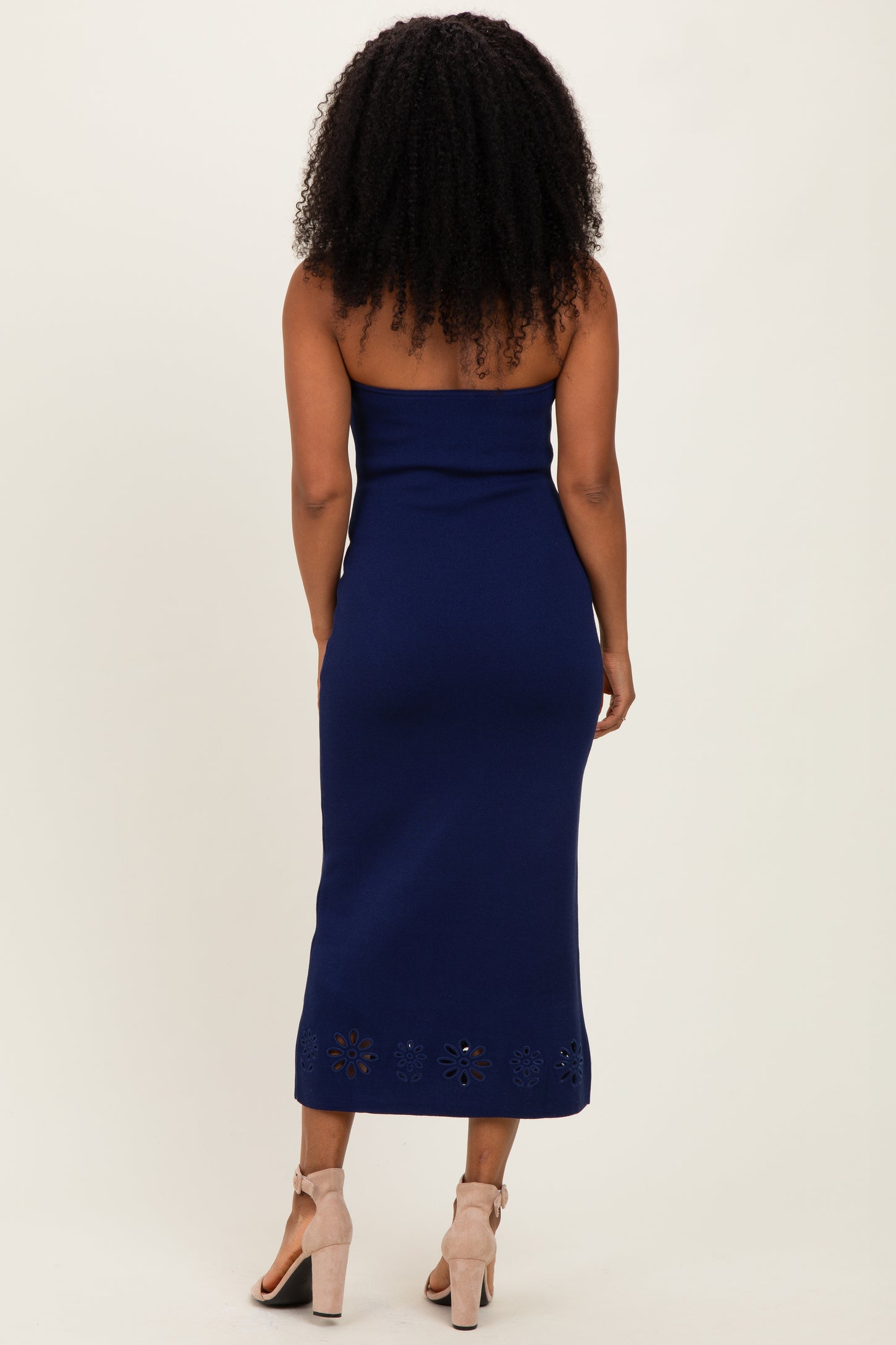 woman wearing a navy blue strapless midi dress with a floral cut-out hem and a fitted silhouette