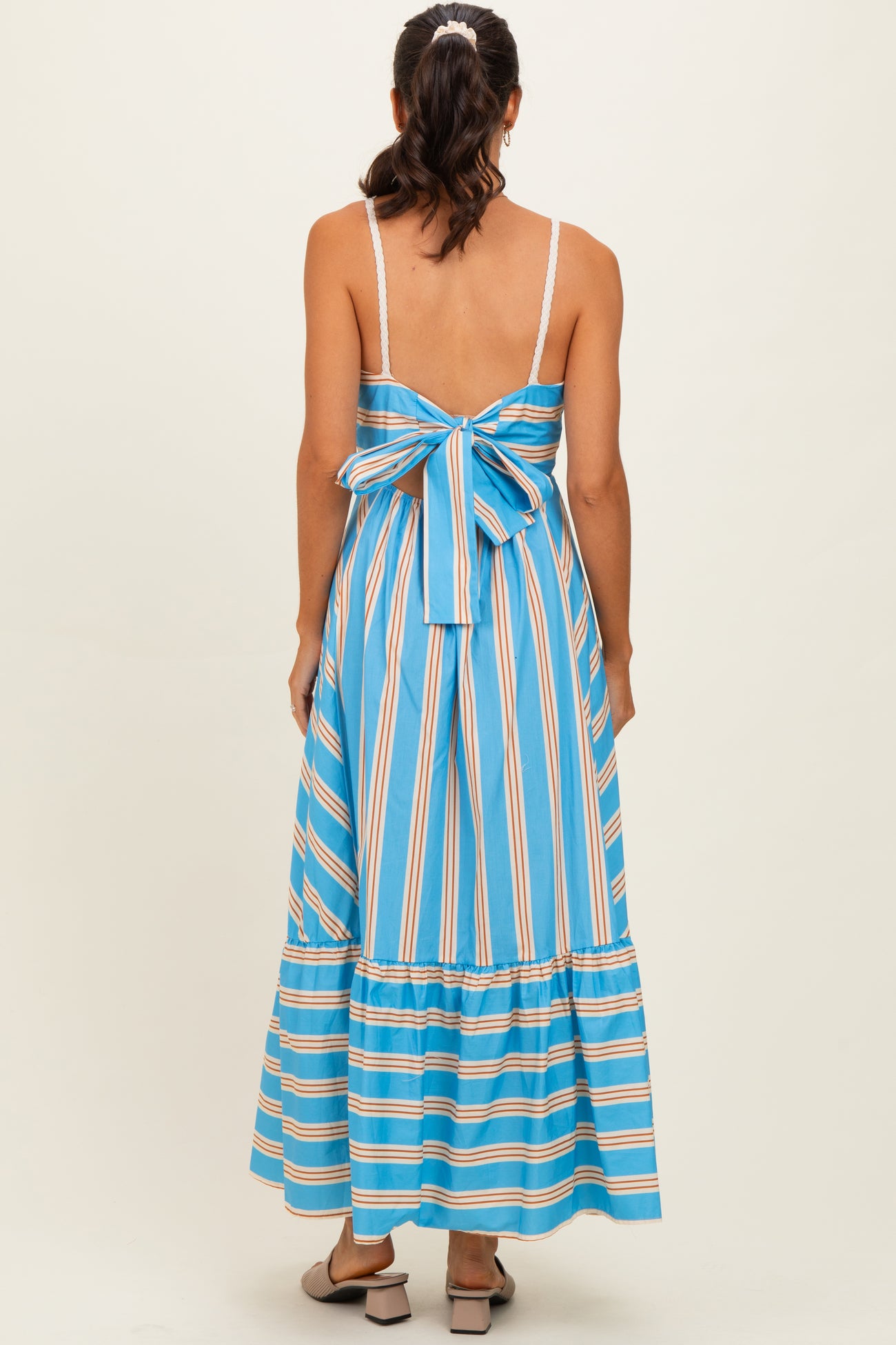 woman wearing a blue and white striped maxi dress with a back bow detail and a tiered skirt