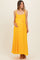woman wearing a bright yellow maternity maxi dress with spaghetti straps and a decorative bow, gently cradling her baby bump